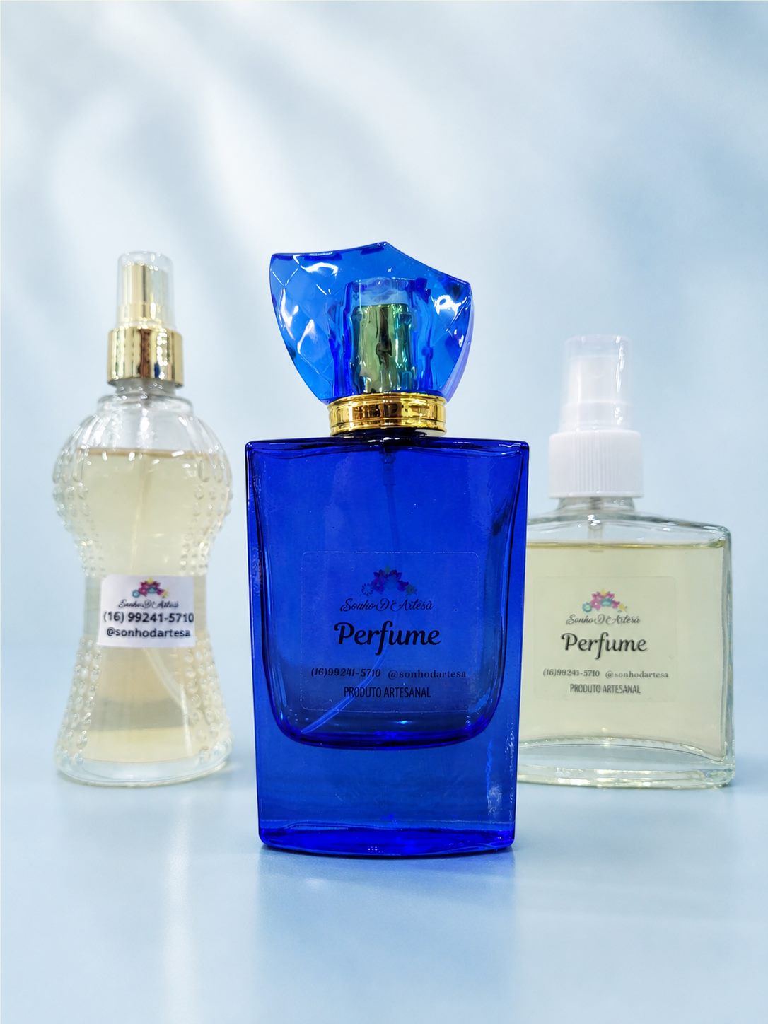 Três perfumes artesanais Sonho D’Artesã em frascos azul e transparentes